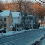 Winter view of a picturesque snowy street with colorful houses and a speed limit sign in a village.
