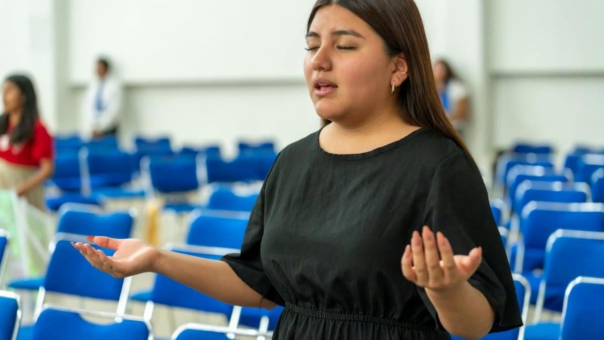 A woman in deep prayer inside an auditorium in Ciudad de México, representing faith and spirituality.