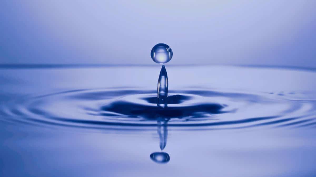 A mesmerizing water droplet captured mid-air with a perfect reflection and ripple effect.