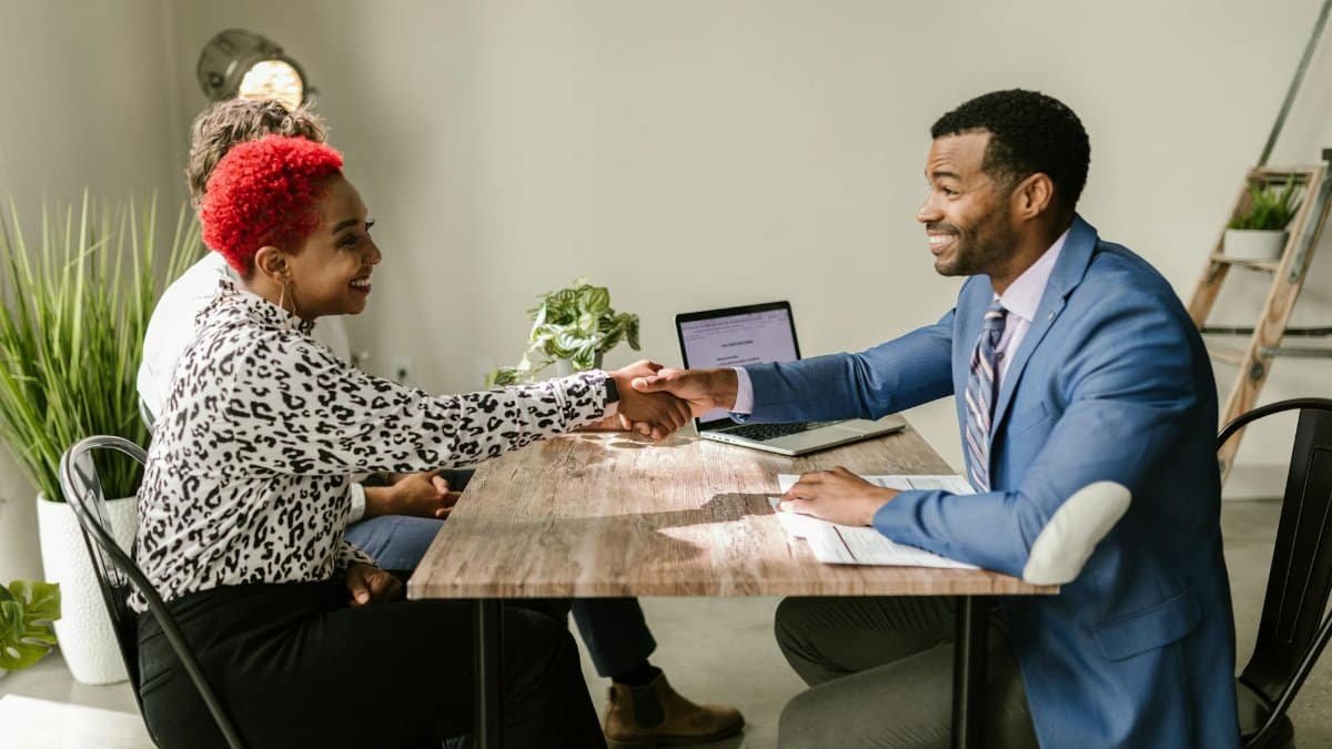 Business professionals shaking hands indoors with smiles, capturing a successful deal or agreement.