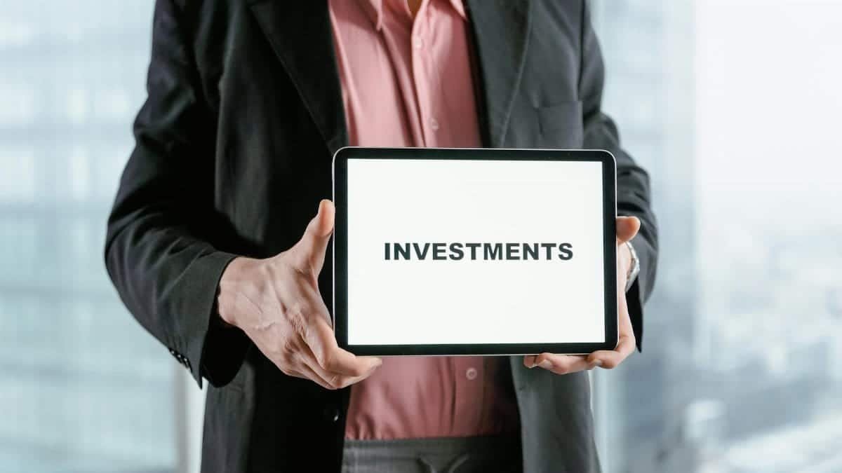 Professional holding a tablet with 'INVESTMENTS' text, ideal for finance and business themes.