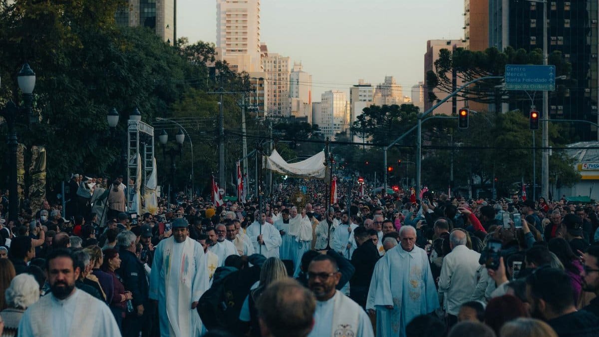 Crowd gathers for a religious procession in a bustling city center.