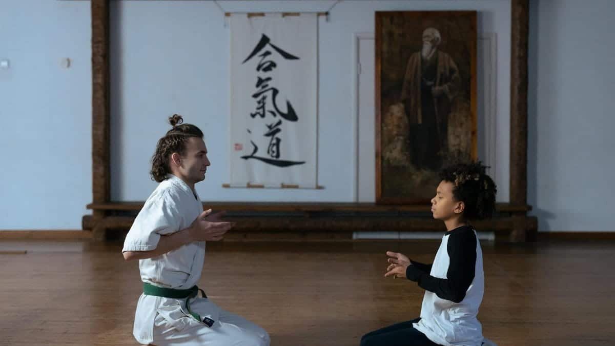 A man and child meditating in a dojo, focusing on martial arts discipline.