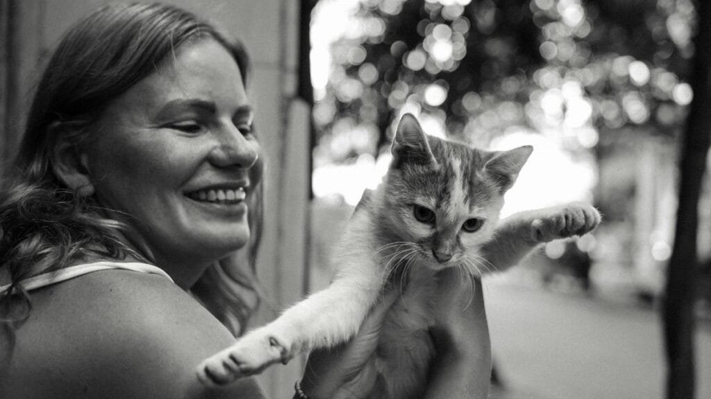 Happy woman holding a playful cat outdoors in Istanbul, capturing a joyful moment.