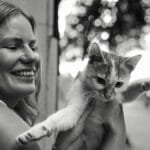 Happy woman holding a playful cat outdoors in Istanbul, capturing a joyful moment.