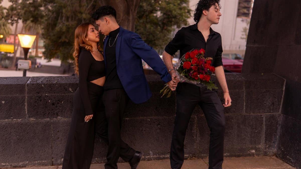 Three people caught in emotional love triangle outdoors at sunset.