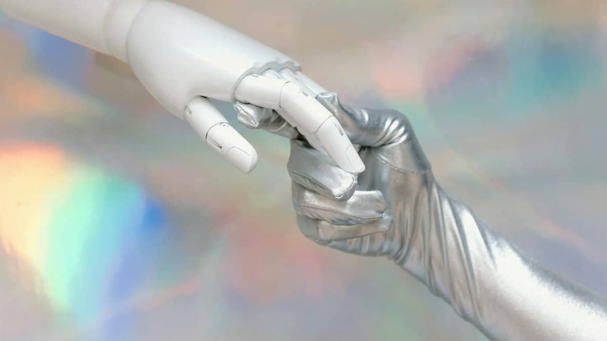 Close-up of a robot hand and silver-gloved hand touching, symbolizing human-robot connection.