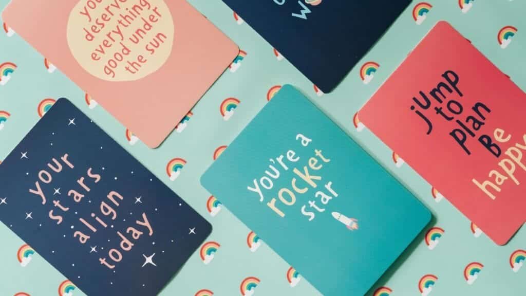 Colorful motivational cards with uplifting messages on a rainbow-themed backdrop.