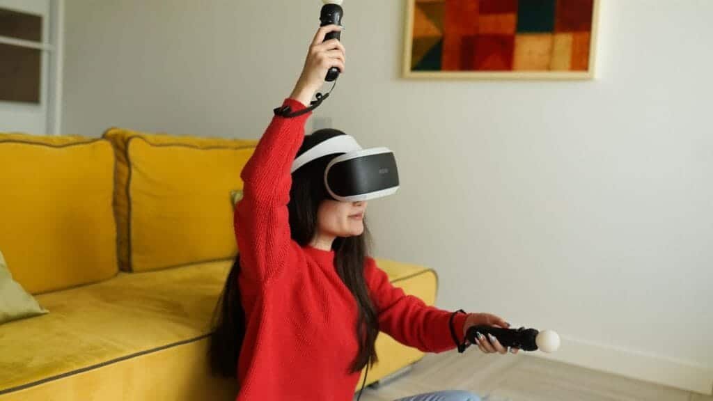 Woman using VR headset and controllers while gaming in a cozy living room setting.