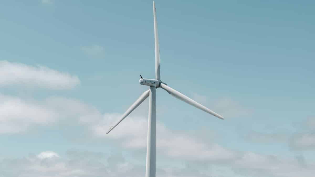 A wind turbine against a blue sky with clouds, symbolizing renewable energy.