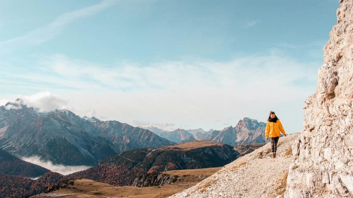 Woman hiking on rocky trail in the scenic Italian Dolomites on a sunny day.