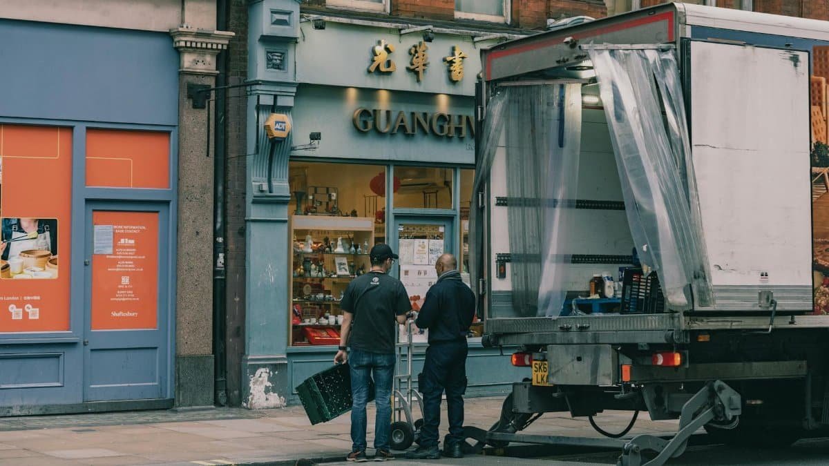 Two men delivering goods to a Chinese store using a truck on a city street.