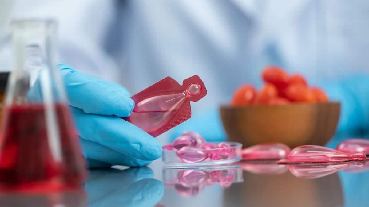 Scientist wearing gloves handling a red liquid vial in a laboratory setting, emphasizing research and medical care.