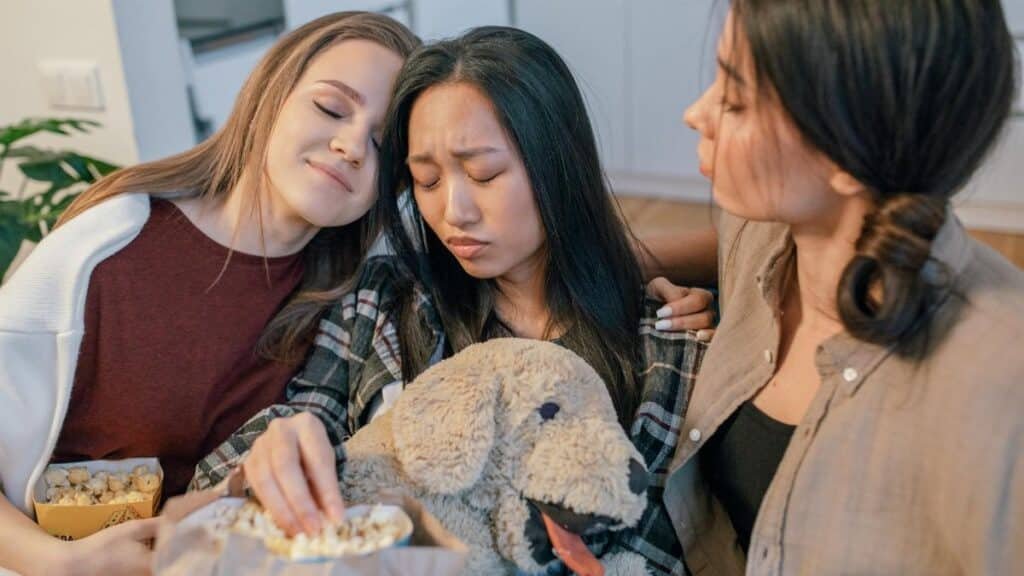 Three women sitting together, sharing popcorn and comfort. Emotional bonds and friendship.