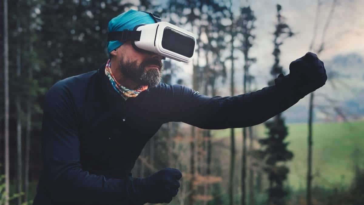 Man using virtual reality headset outdoors, immersed in a VR experience amid nature.