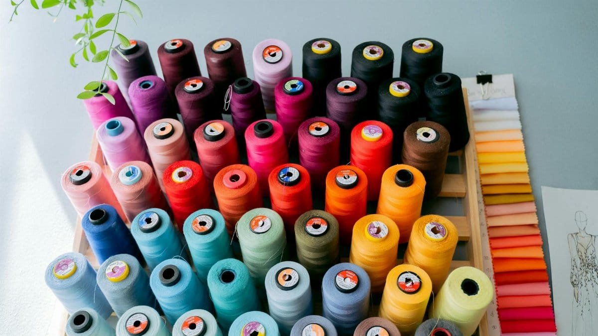 A vibrant collection of sewing threads displayed alongside fabric swatches in a creative studio.