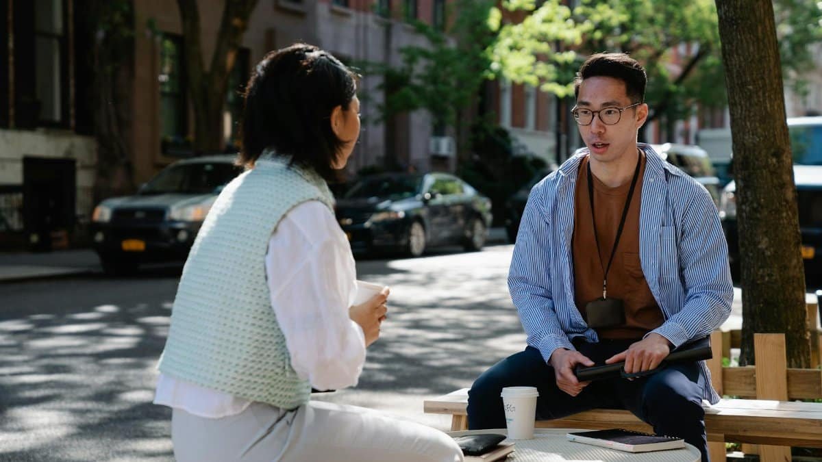 Two colleagues engaged in a conversation outdoors on a sunny day in an urban street.