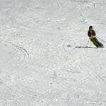 A skier expertly navigates down a snowy slope at a ski resort, showcasing winter sports excitement.