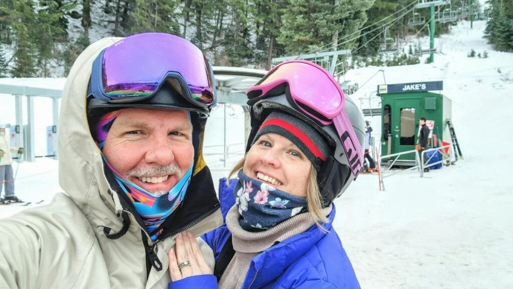 A happy couple in ski gear poses at Sundance Resort ski lift, Utah.