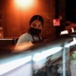 Portrait of a masked employee working behind a glass counter, creating a safe service environment in Richmond, Virginia.