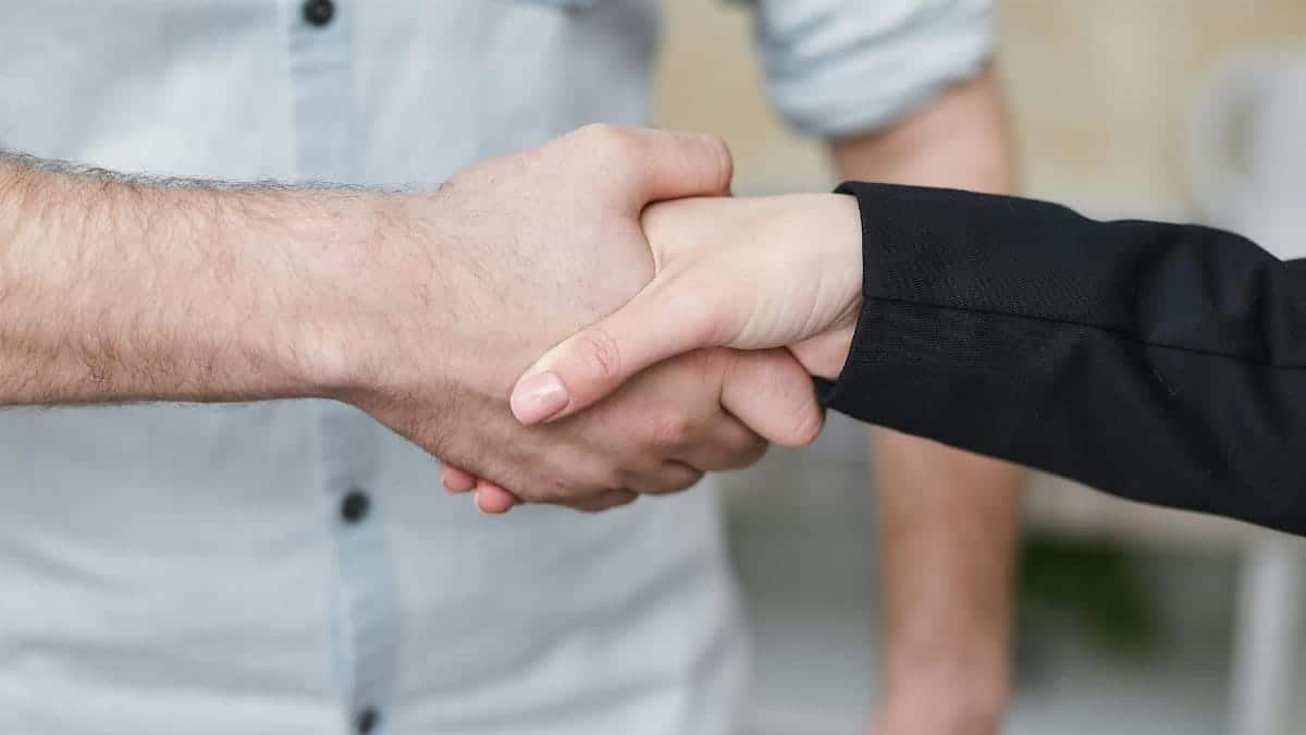 Close-up of two individuals shaking hands symbolizing business agreement and partnership.