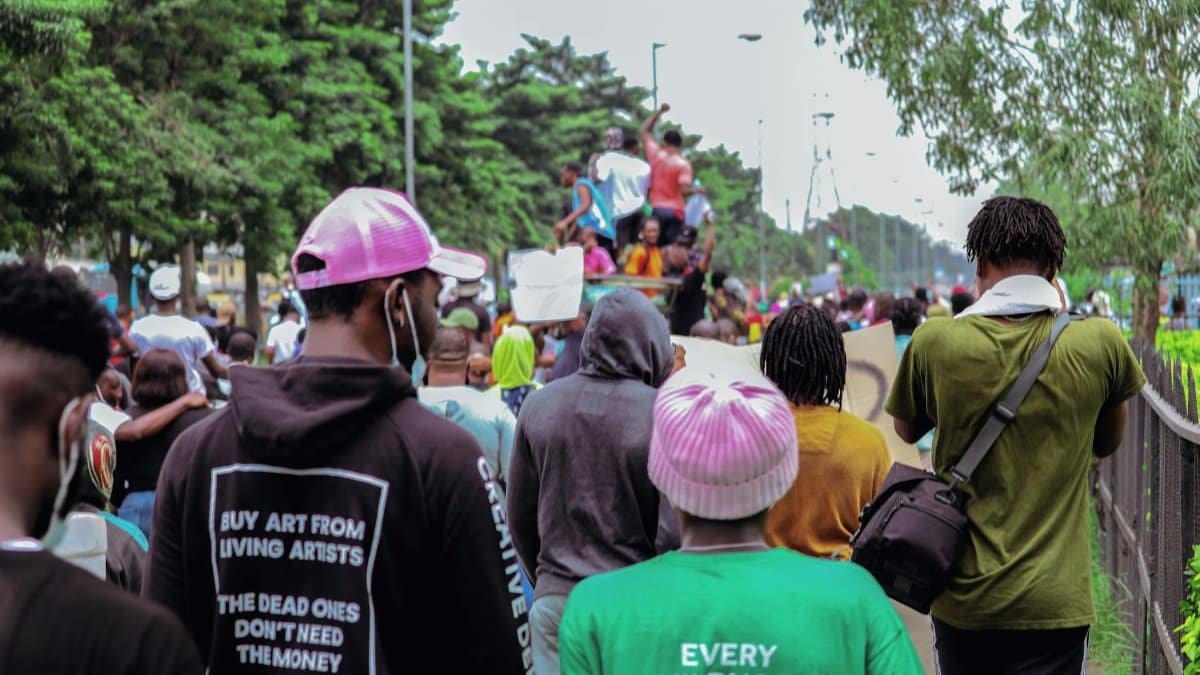 A crowd of diverse individuals at a street event captured from behind.