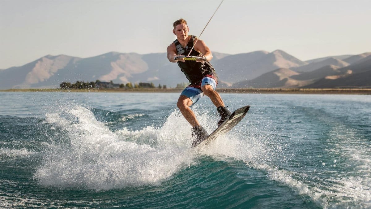 Exciting wakeboarding action on a sunny day with mountain backdrop. Perfect for sports and adventure enthusiasts.