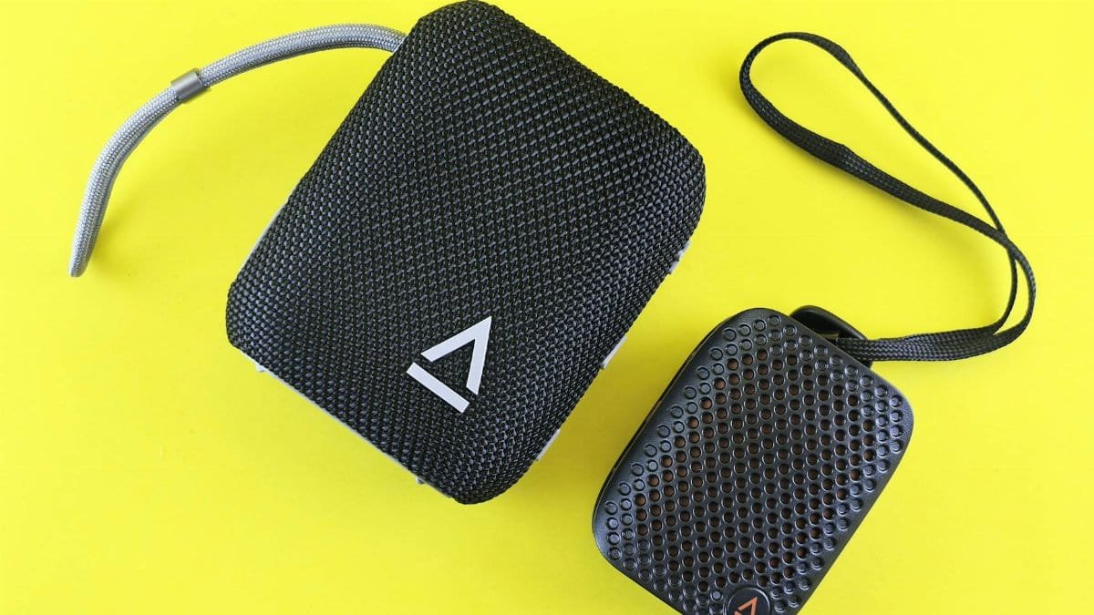 Two portable black speakers with textured surfaces on a bright yellow background, perfect for tech designs.