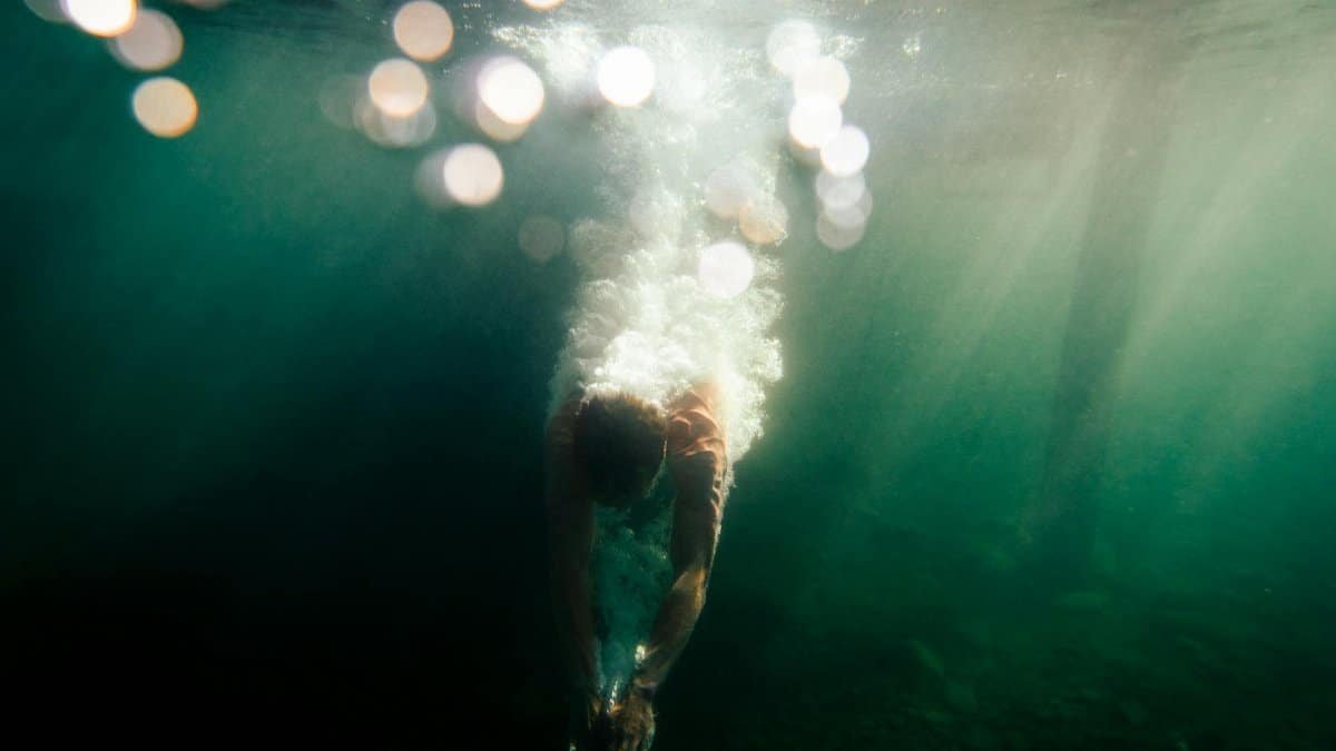 Dynamic underwater shot capturing a diver in motion with a splash, set in vibrant blue waters.