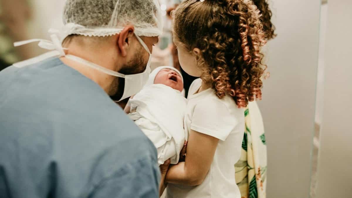 A happy family moment as a young girl meets her newborn sibling in the hospital.