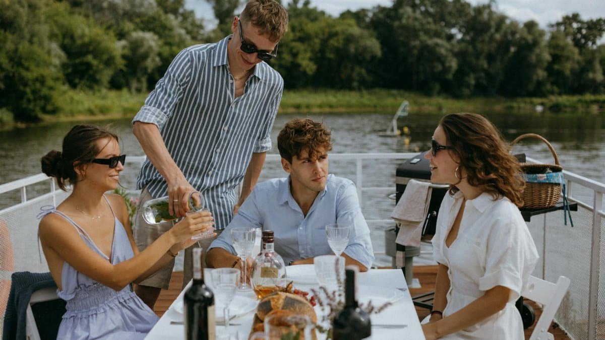 Four friends enjoying a scenic boat dinner party on a sunny day.