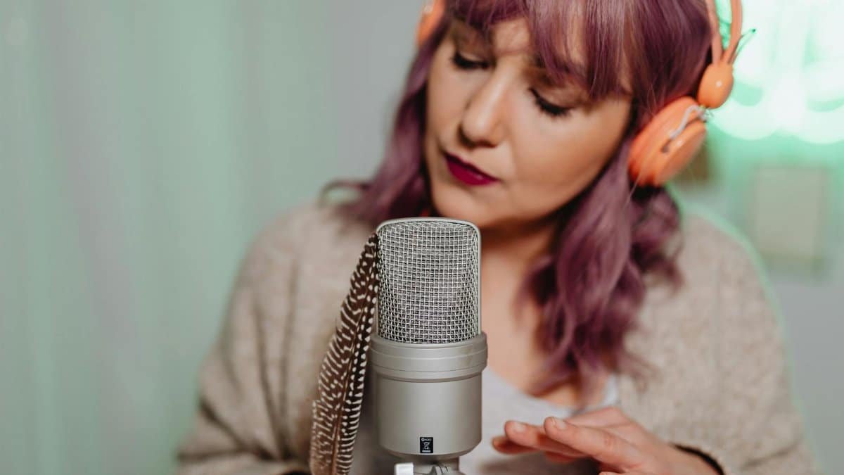 Close-up of ASMR artist with microphone, feather, and headphones.