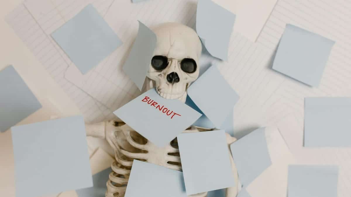 A skeleton covered in sticky notes with 'burnout' on one, symbolizing work stress and exhaustion.