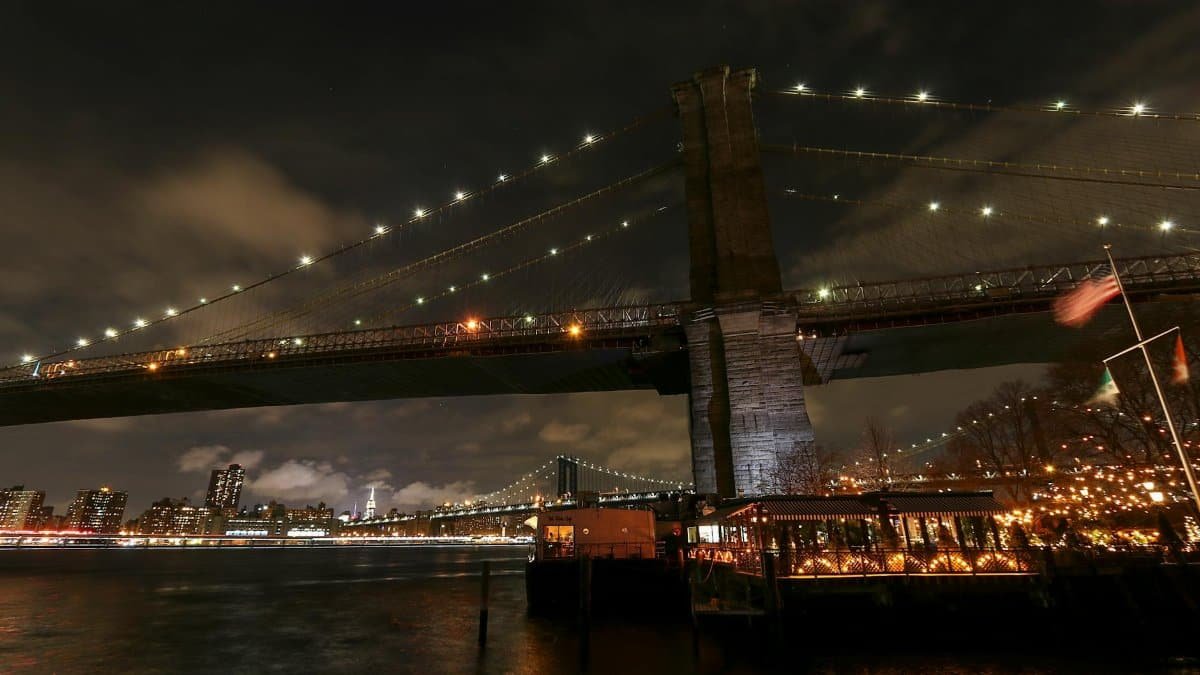 Captivating view of Brooklyn Bridge at night with New York City skyline in the background.