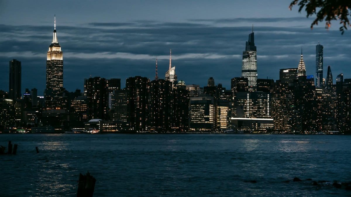 Contemporary illuminated towers located in central district on coast of rippling river in New York at night
