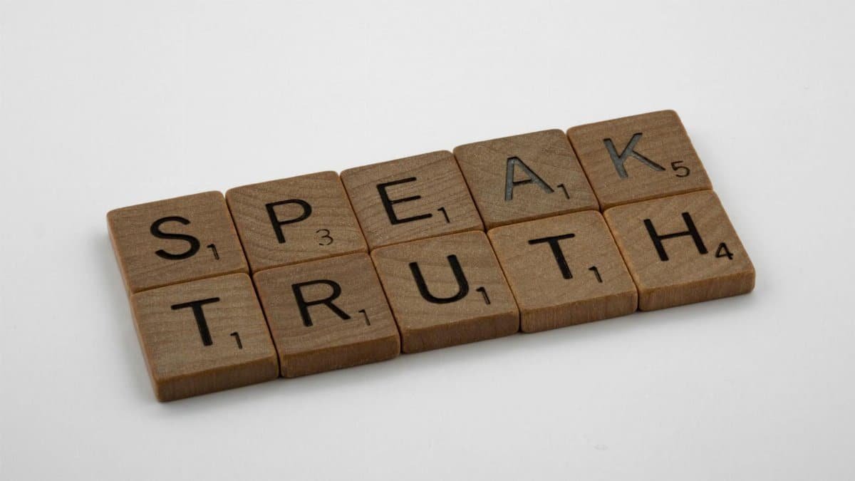 Wooden Scrabble tiles forming the words 'Speak Truth' on a white background.