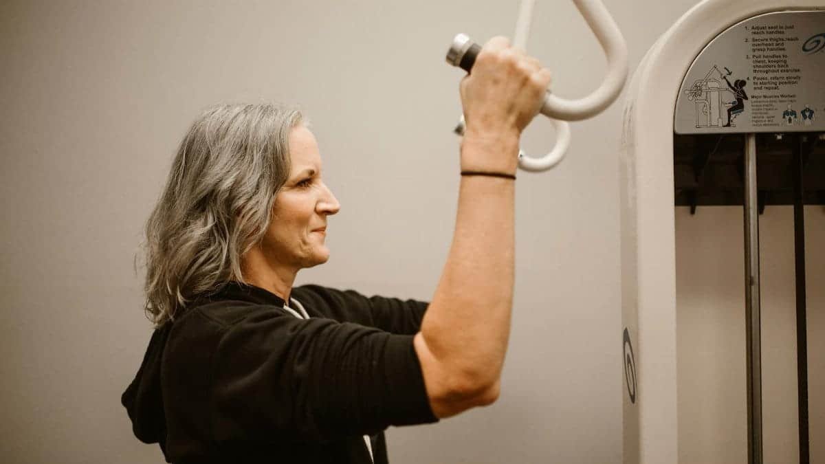 Active senior woman working out on gym equipment, focusing on strength and wellness.