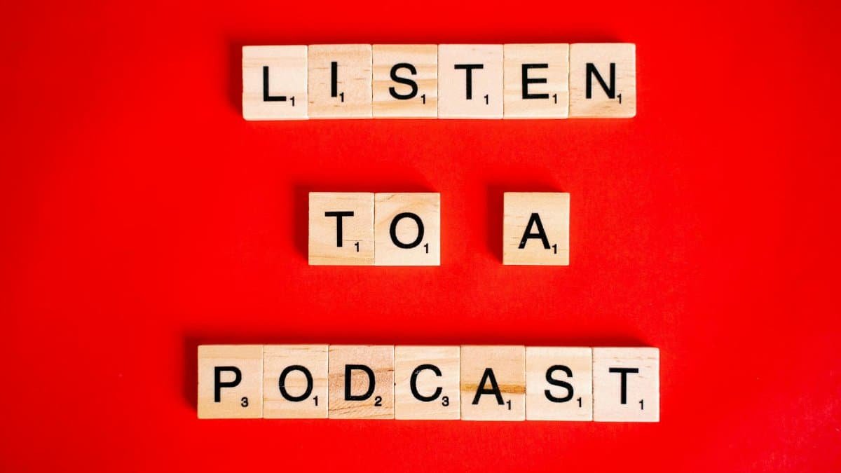 Scrabble tiles on red background forming the phrase 'Listen to a Podcast'.