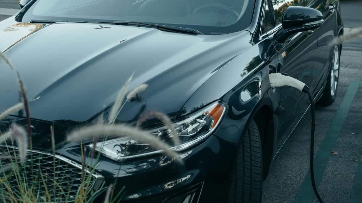 Close-up of an electric car charging at a station in a city parking lot, showcasing clean energy technology.