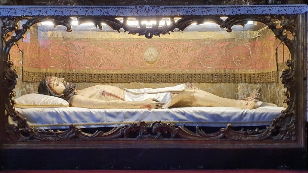 Intricately carved sculpture of Jesus in a glass display at a church in Porto, Portugal.