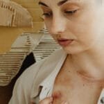 Close-up of a woman showing healing bruises on her chest with a thoughtful expression.
