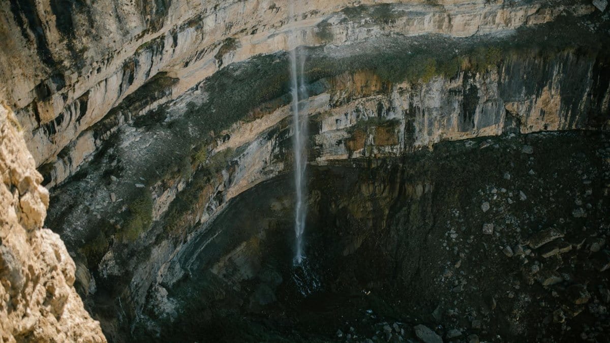 A breathtaking aerial view of a waterfall cascading down a rugged canyon, showcasing nature's raw beauty.