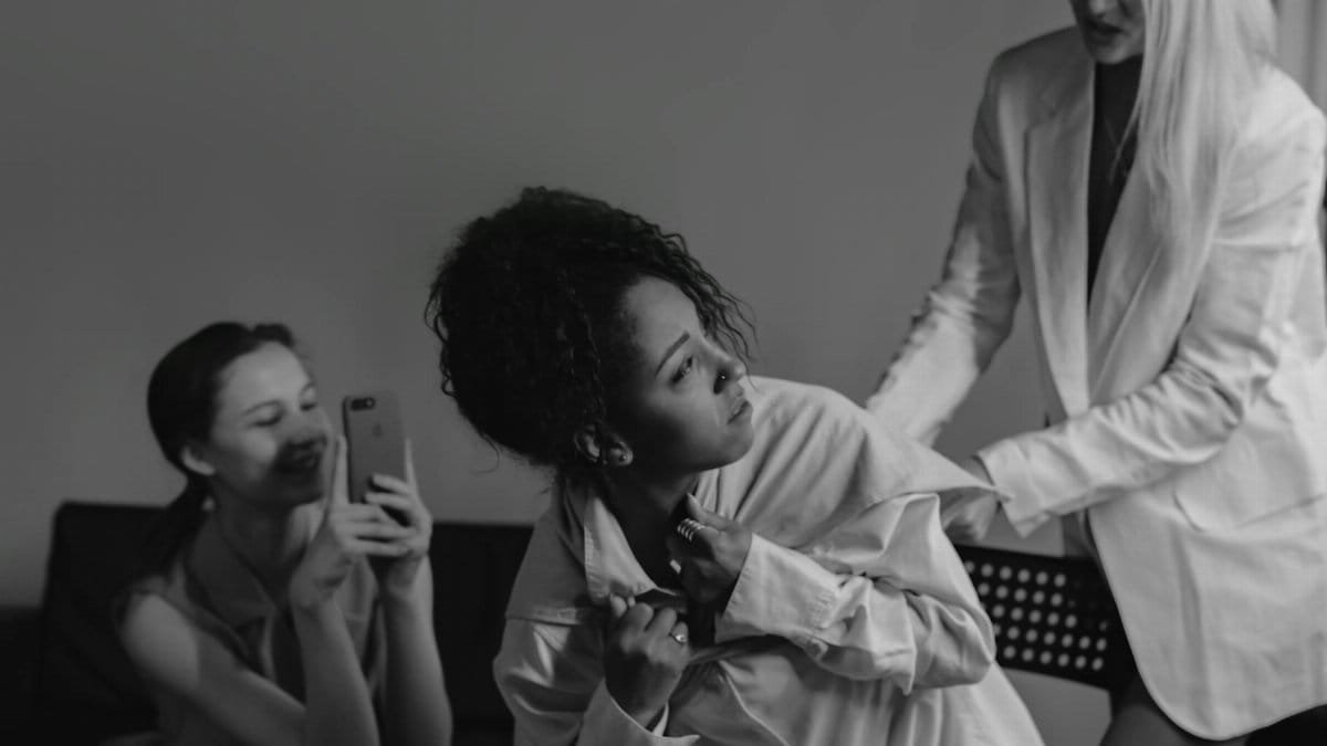 A dramatic black and white photograph capturing conflict and tension among diverse women.