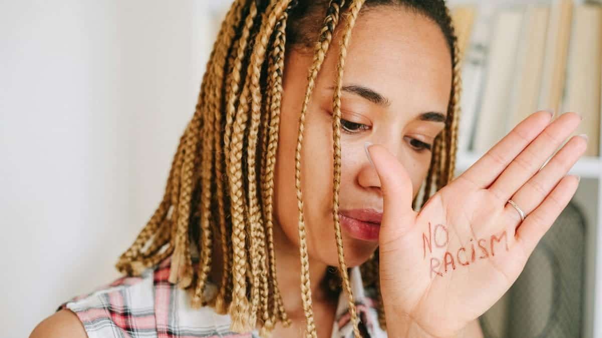 Close-up portrait of a woman with 'No Racism' written on hand, promoting anti-racism message.