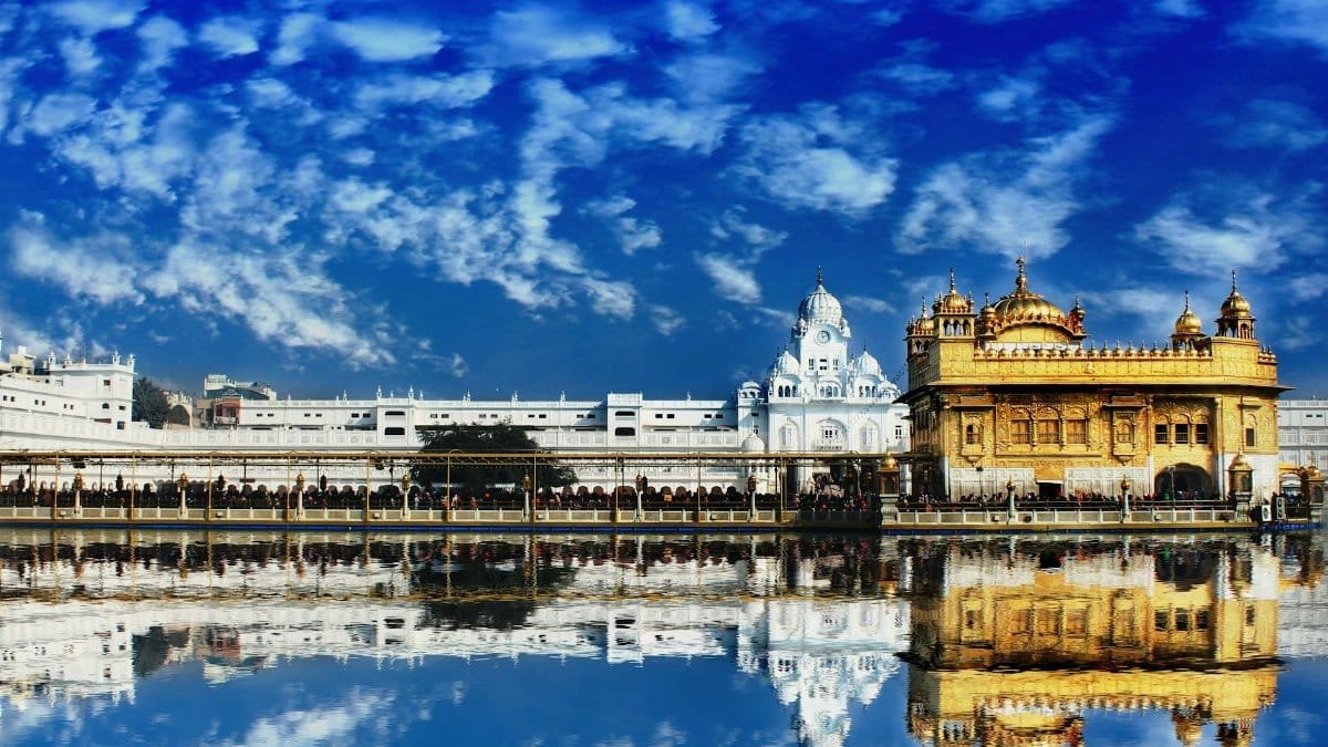 The Golden Temple, Harmandir Sahib, in Amritsar beautifully reflected in water with a vivid blue sky.