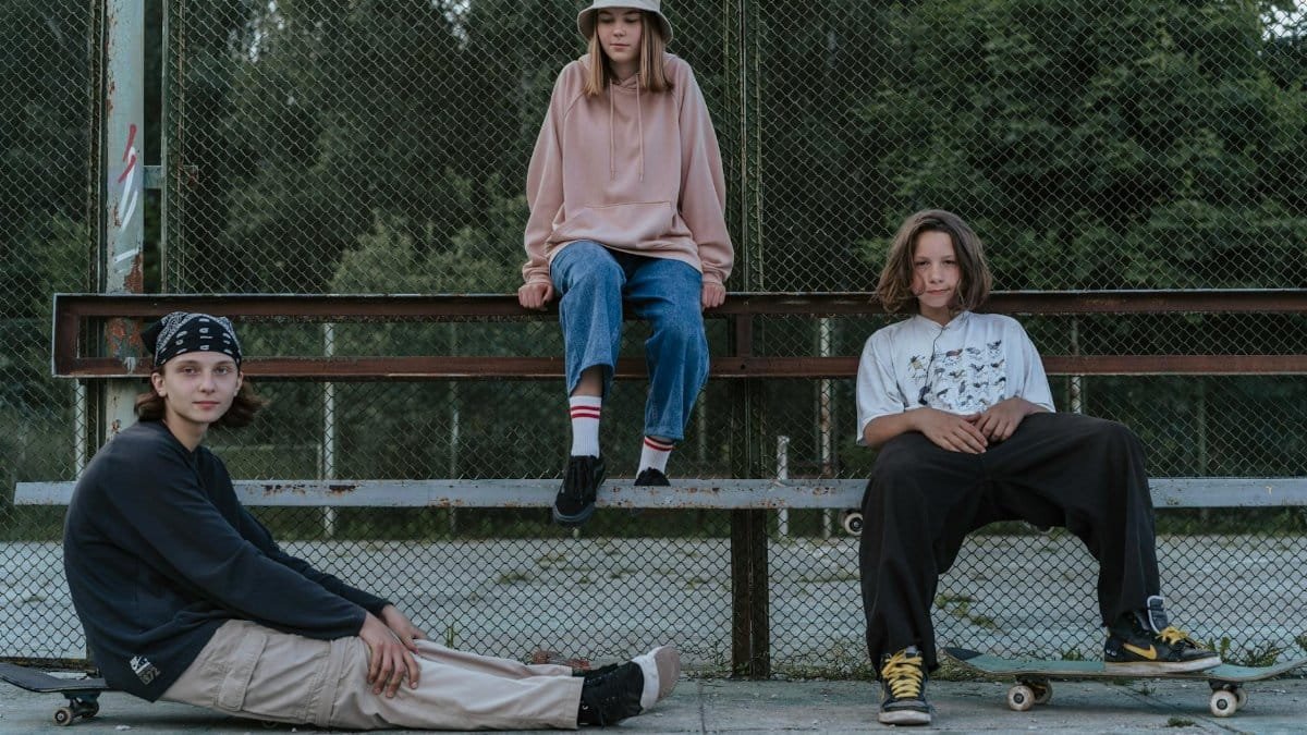 Group of teenagers hanging out together with skateboards at a park.
