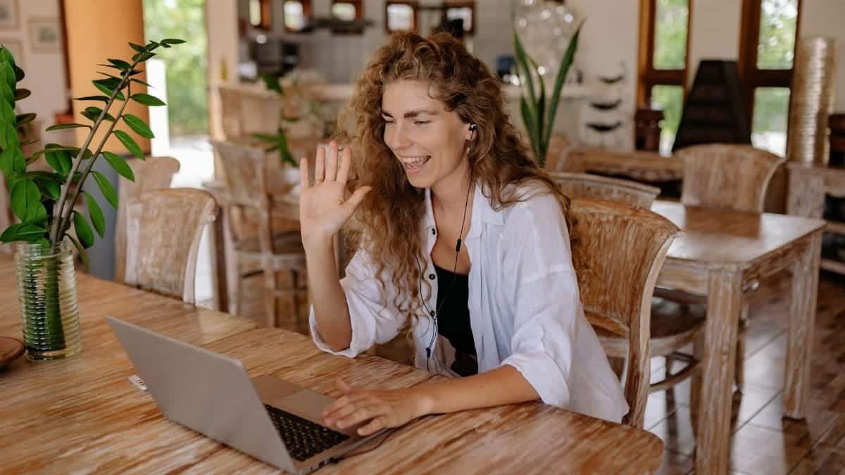 Smiling woman having a video call in a home-like setting with laptop.