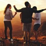 Joyful group of young adults enjoying a sunset view in a mountainous landscape in Brazil.