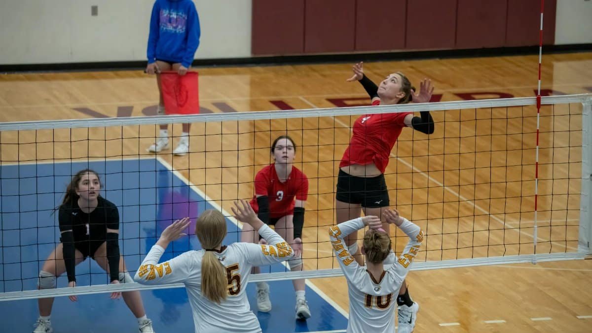 Women athletes playing competitive volleyball indoors at Rochester, MN court.