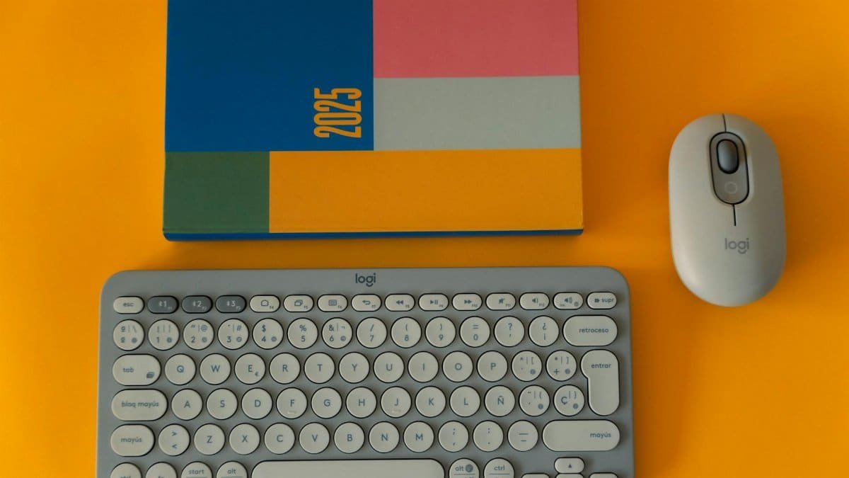 Flat lay of a 2025 planner, keyboard, and mouse on a vibrant yellow background.